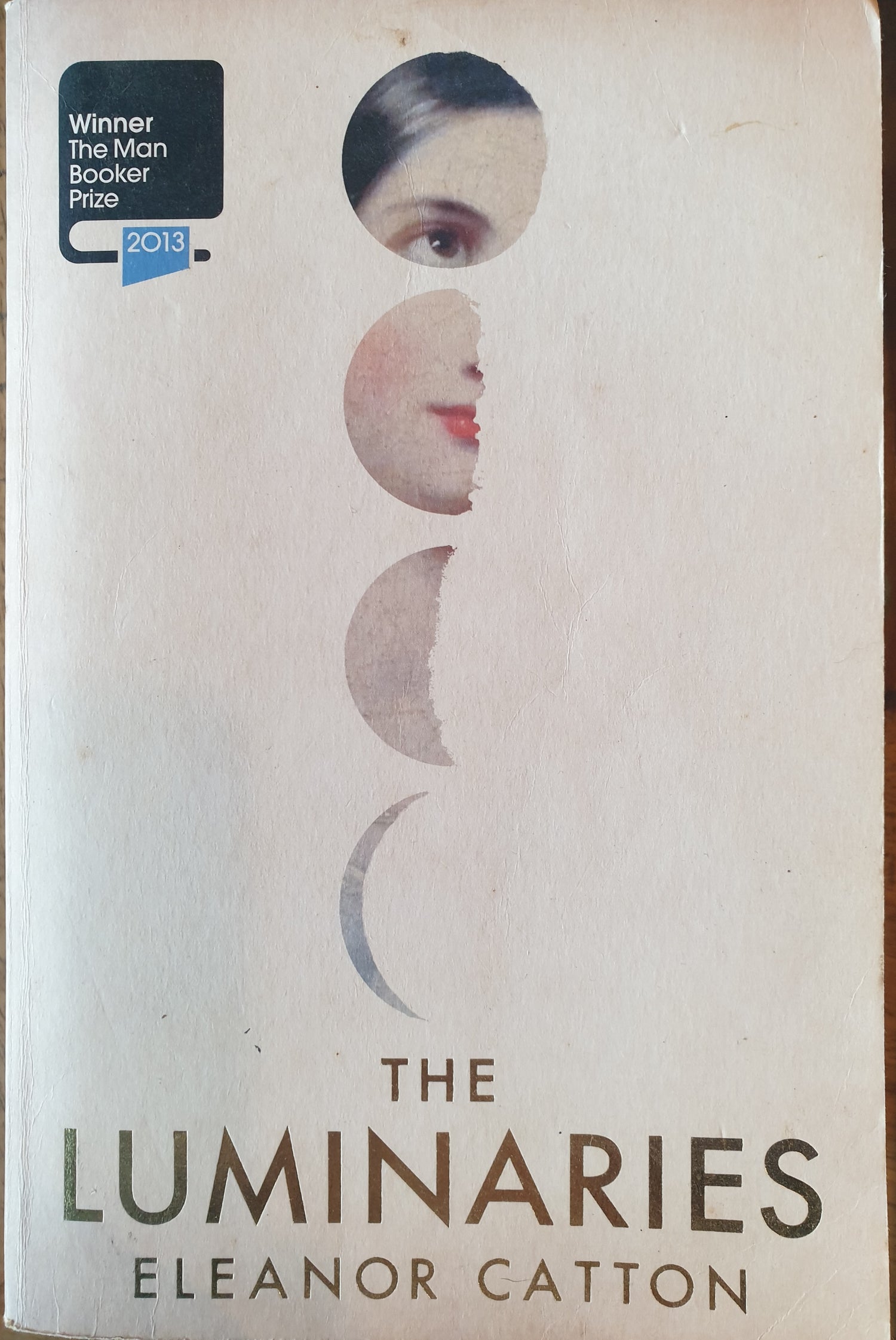 Book cover of 'The Luminaries' by Eleanor Catton with a stylized face design.